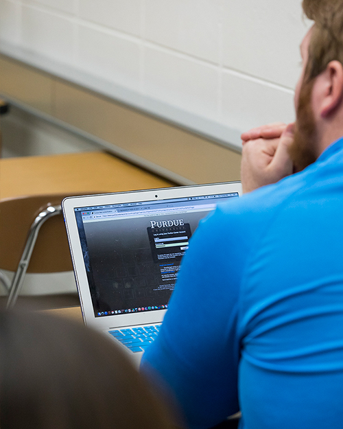 Student listening to professor wit laptop open