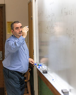 A PNW faculty member writes an equation on a white board