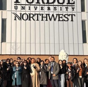 PNW students posing in front of the NILS building with their new passports in hand