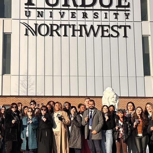 PNW students posing in front of the NILS building with their new passports in hand