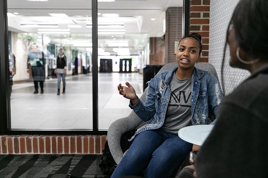 A PNW student chats in an office.