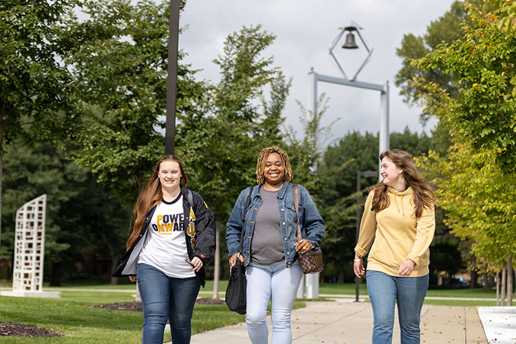 PNW students walk across campus, with the PNW Bell Tower visible in the background