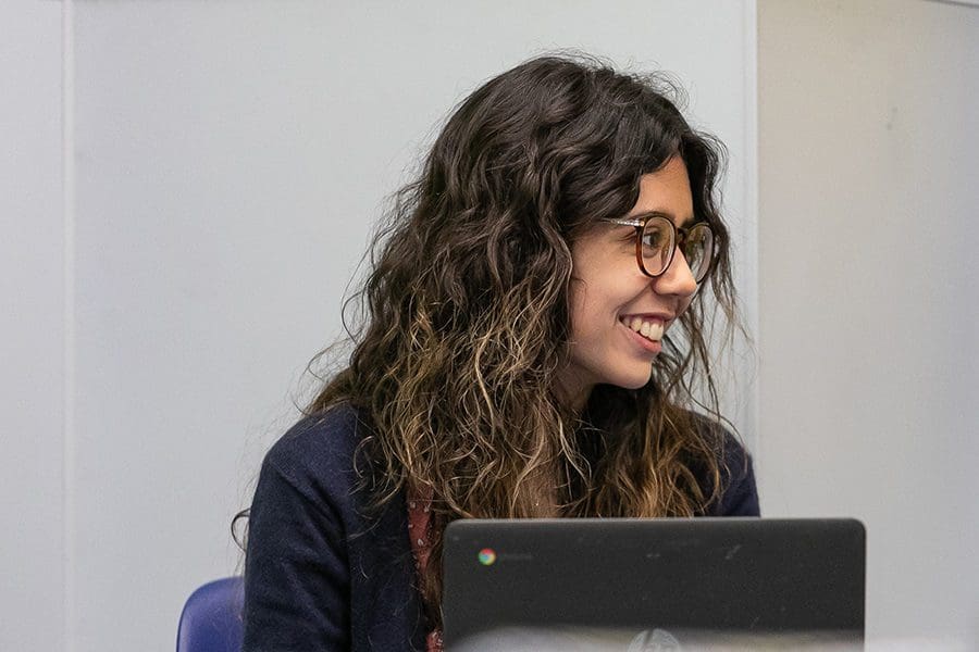 Student Madeline Clement smiles over her computer
