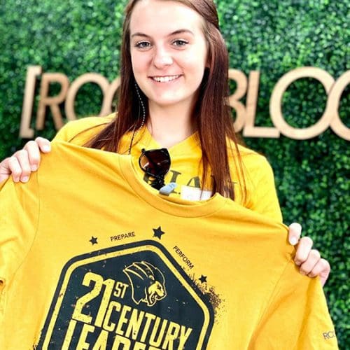 A student holds a 21st century leaders shirt.