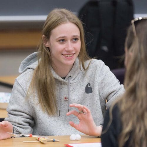 A student sits at a wooden table.