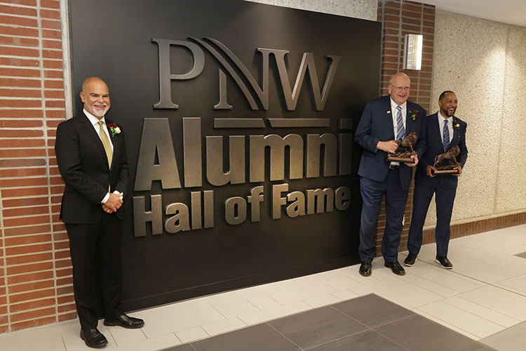 PNW 2023 Alumni Hall of Inductees Alfredo “Al” Sori, Stewart “Stu” McMillan and Robert Johnson III in front of the Alumni Hall of Fame Display in the Student Union and Library Building