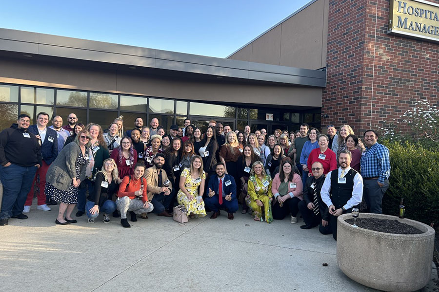 A group of people pose outside of the Hospitality and Tourism Management Building