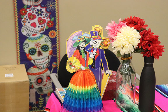 A paper dia del los muertos display in front of flowers