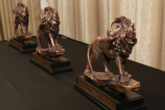 Three bronze lion PNW Alumni Hall of Fame awards sit on a black table cloth