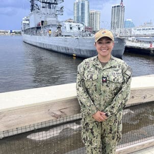 Alyssa Gomezdelacasa stands in uniform in front of a port