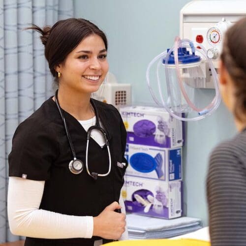 A PNW nursing student stands in a simulated exam room.