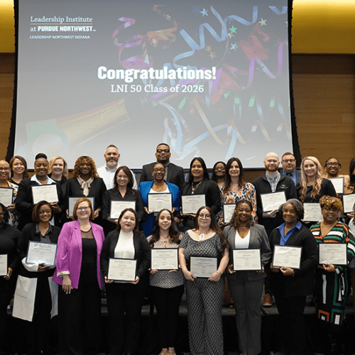 A group of individuals pose together in front of a screen that says "Congratulations! LNI 50 Class of 2025"