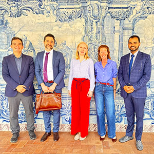 Five people pose in front of a wall with a mural on it.