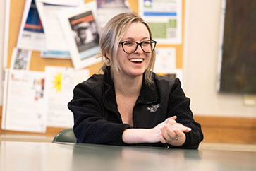 A young woman in glasses laughs in the classroom