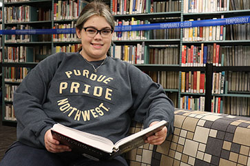 PNW student Victoria Archuleta reads a book in the library