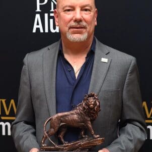 A man in a suit holds a lion sculpture on a base.