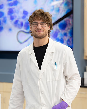 A student poses in a white lab coat