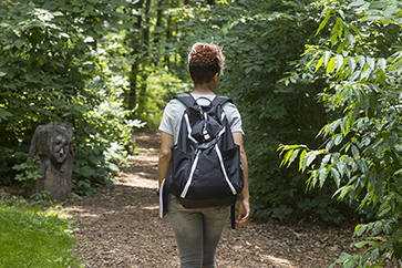 A student wearing a backpack walks down a trail