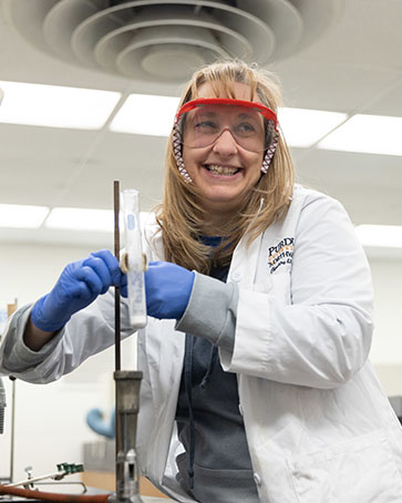 a student in a lab coat and classes work with test tubes