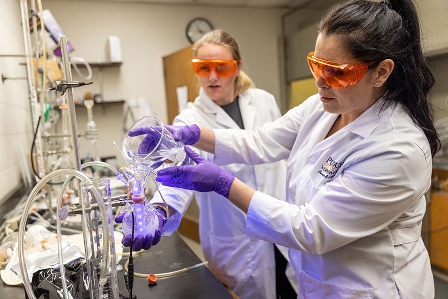 Two chemistry students work in a lab.