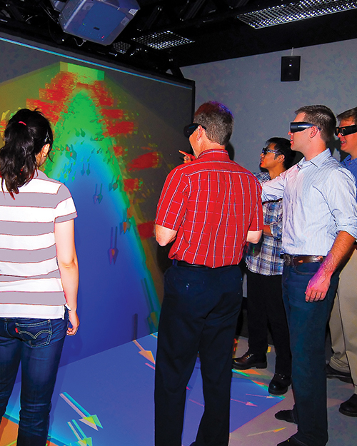 Individuals in 3D glasses looking at screen in auditorium