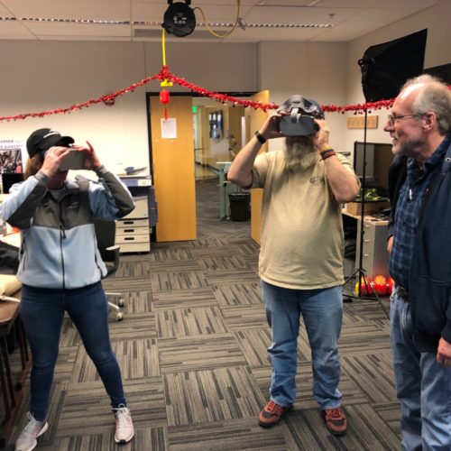 Visitors participates in hands-on experiences of AR & VR projects in the visualization lab. Participants are standing while holding VR goggles.