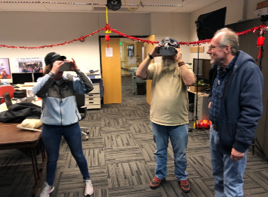 Visitors participates in hands-on experiences of AR & VR projects in the visualization lab. Participants are standing while holding VR goggles.
