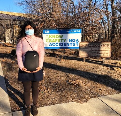 Individual standing outdoors in front of Deerfield Woods Center commercial signage holding VR headset in large black case