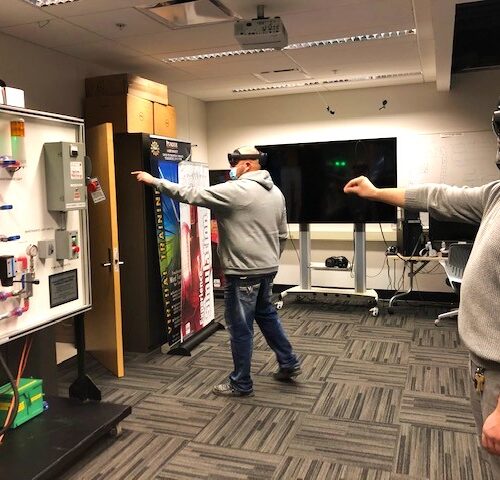 Visitors participate in hands-on experiences of AR & VR projects in the visualization lab. Participants are standing while wearing a tethered VR headsets