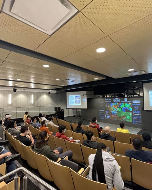 People looking at screen in auditorium seated in rows of chairs