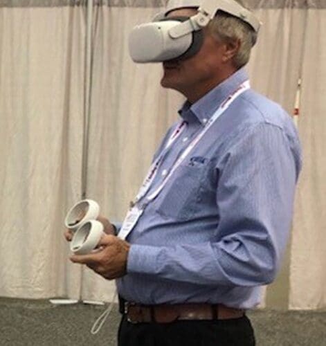 A person standing in a VR headset with VR controllers in their hands.