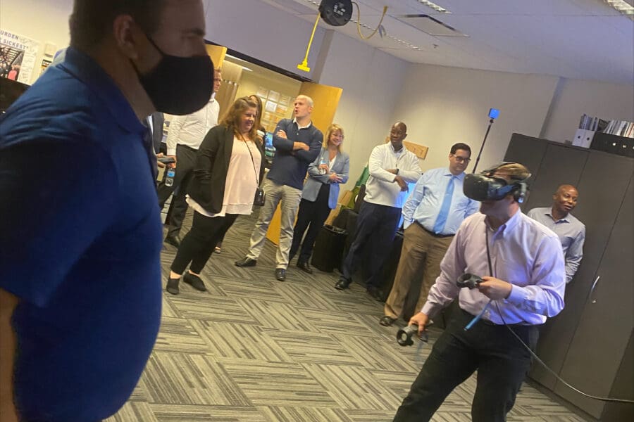 Visitor partiticpates in hands-on experiences of AR & VR projects in the visualization lab. Participant is standing while wearing a tethered vr headset and manipulating had held controllers.