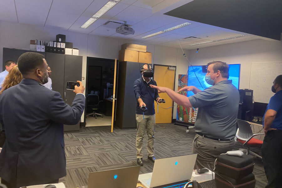 Visitor partiticpates in hands-on experiences of AR & VR projects in the visualization lab. Participant is standing while wearing a tethered vr headset and manipulating had held controllers.