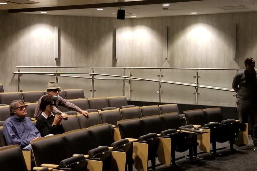 People in 3D glasses looking at screen in auditorium seated in rows of chairs