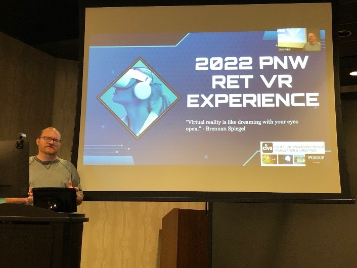Individual standing and talking in front of screen featuring PowerPoint slide at podium in auditorium