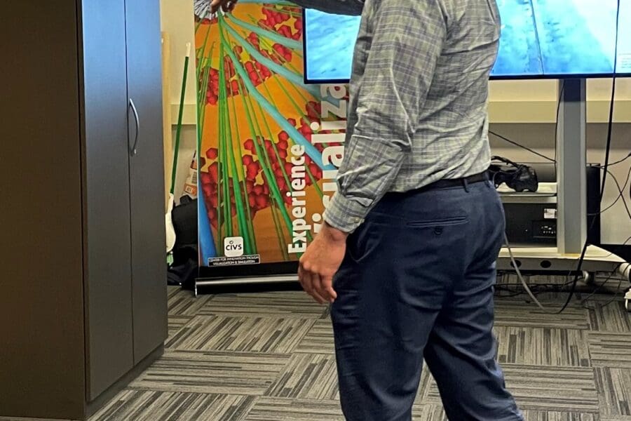 Visitor participates in hands-on experiences of AR & VR projects in the visualization lab. Participant is standing while wearing a tethered VR headset .