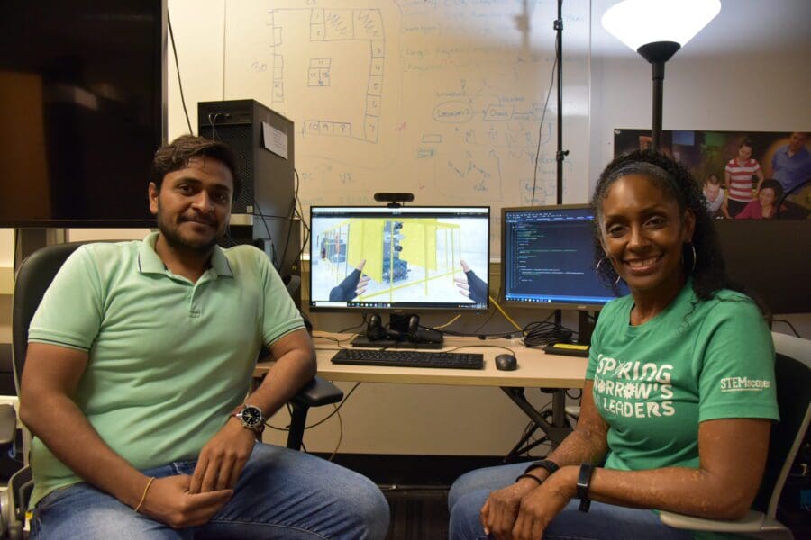 Man and woman seated in front of computer on desk featuring digital animation