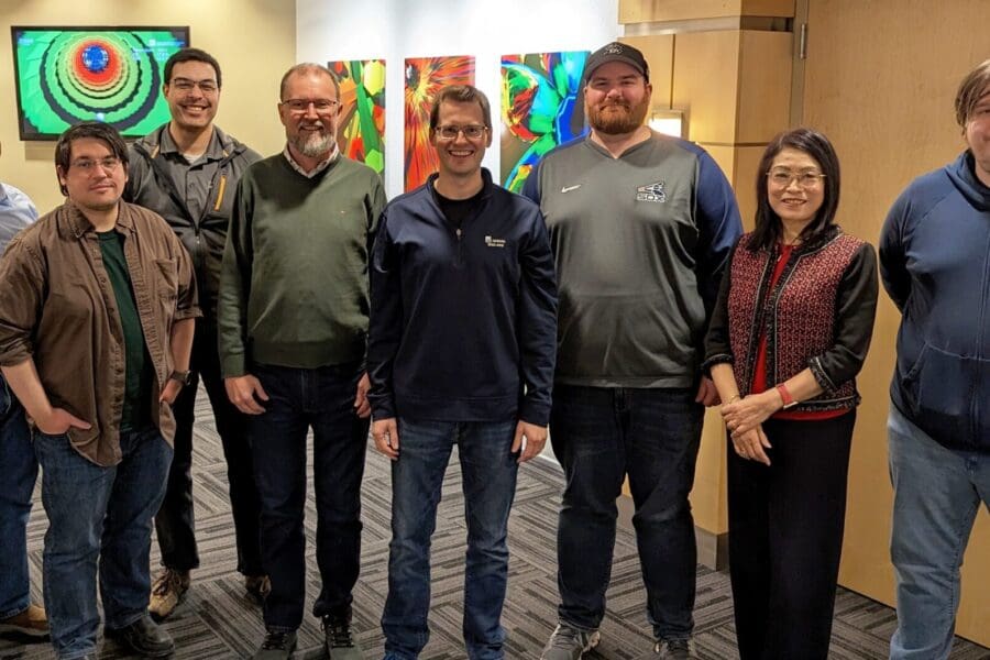 A small group of people stand together in a row in an office lobby