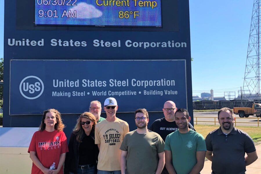Visitors standing outdoors in front of U.S. Steel Gary Works commercial signage
