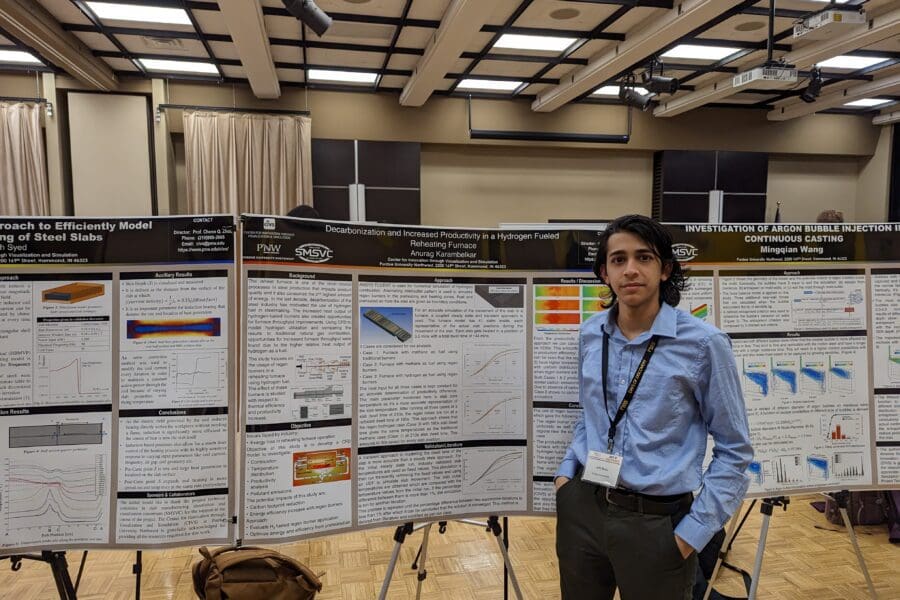 Student in a professional business attire standing in front of academic poster in presentation hall