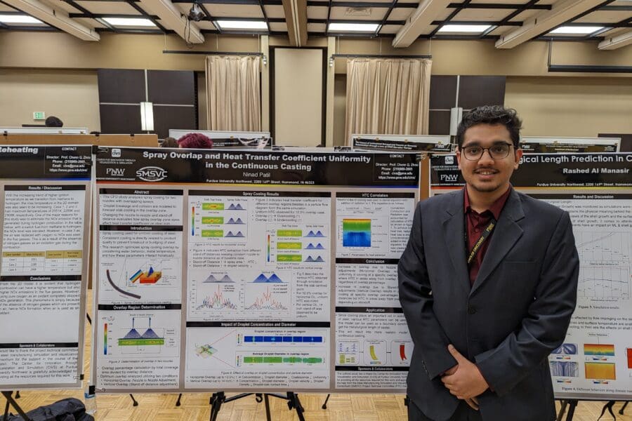 Student in a professional business attire standing in front of academic poster in presentation hall