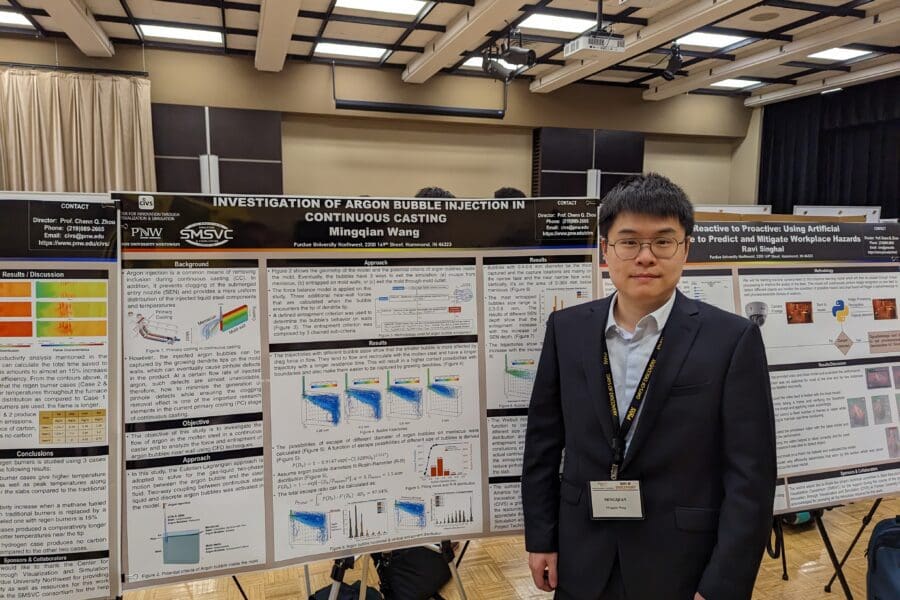 Student in a professional business attire standing in front of academic poster in presentation hall