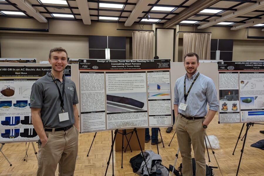 Students in a professional business attire standing in front of academic poster in presentation hall