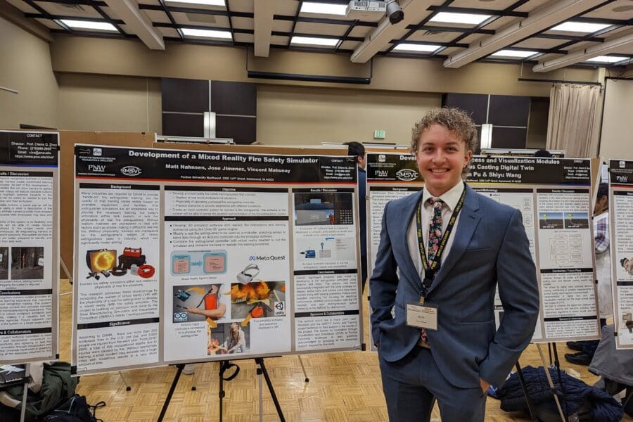 Student in a professional business attire standing in front of academic poster in presentation hall