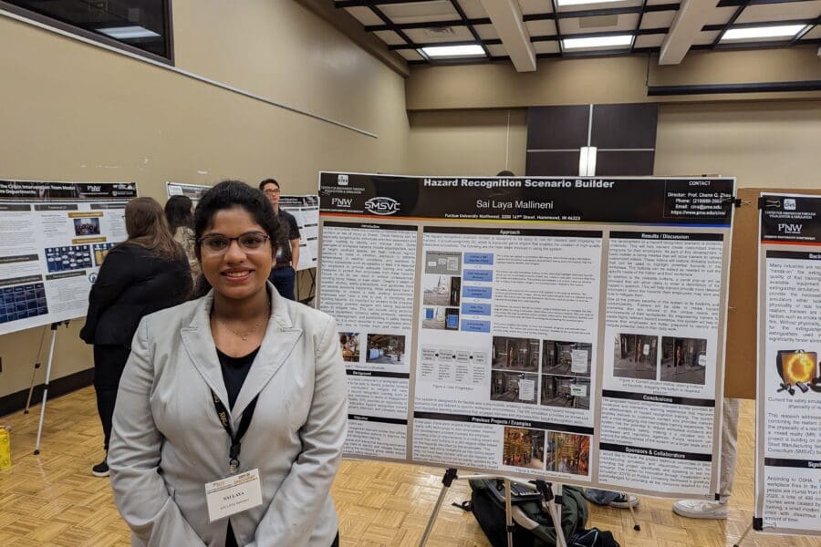 Student in a professional business attire standing in front of academic poster in presentation hall