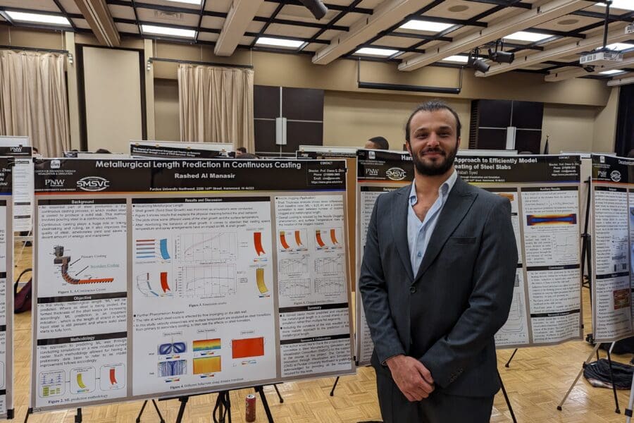 Student in a professional business attire standing in front of academic poster in presentation hall