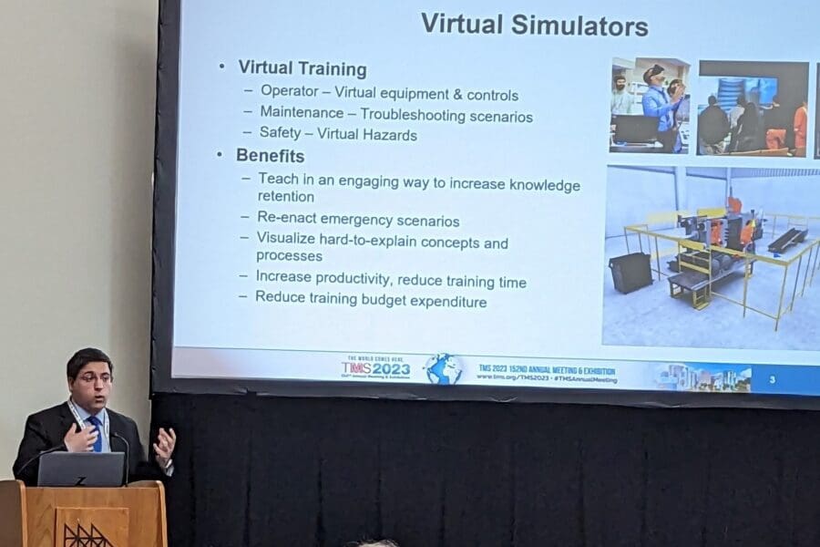 Man standing in front of screen featuring PowerPoint slide at podium in conference room