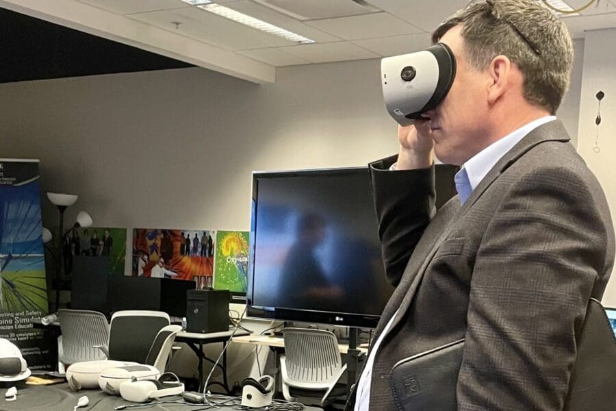 Visitor participates in hands-on experiences of AR & VR projects in the visualization lab. Participant is standing while holding VR goggles.