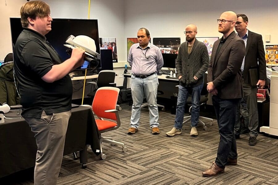 CIVS research engineer, Kyle Toth gives demonstration to visitors holding a specialty VR headset in the visualization lab.