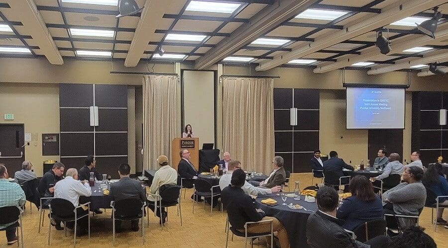 Chenn Zhou standing at podium in front of guests seated at several round tables